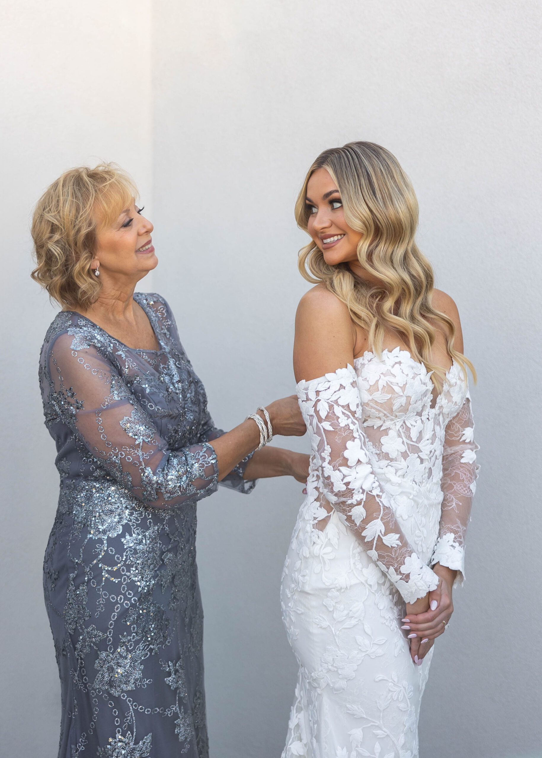 Bride putting on dress with mom